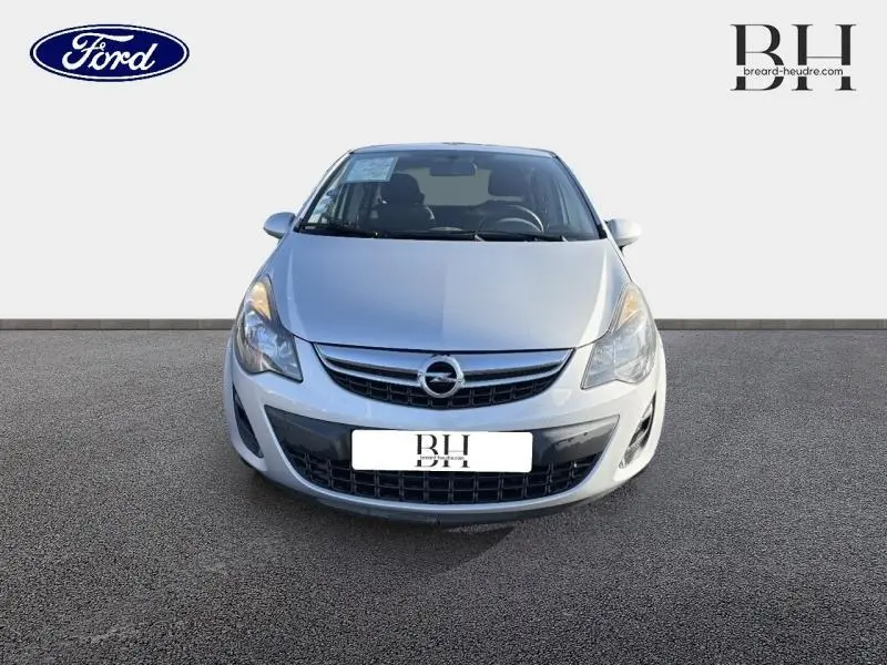 Vue frontale d'une Opel Corsa gris minéral 2014 avec calandre chromée et phares halogènes allumés.