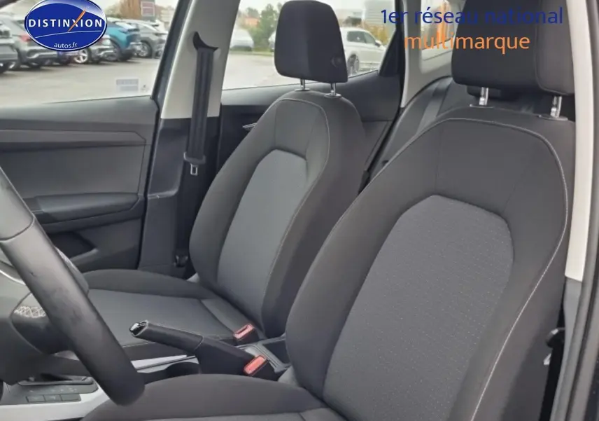 Vue intérieure côté avant droit montrant les sièges tissu gris et le levier de frein à main d'une SEAT Arona 2025.