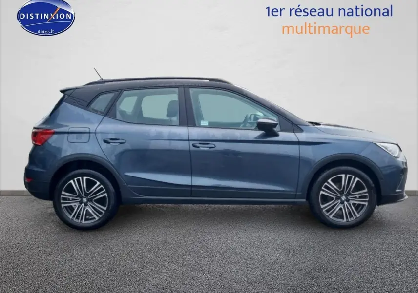 Vue latérale droite d'un SEAT Arona gris magnétique 2025 avec jantes 17 pouces et barres de toit noires.