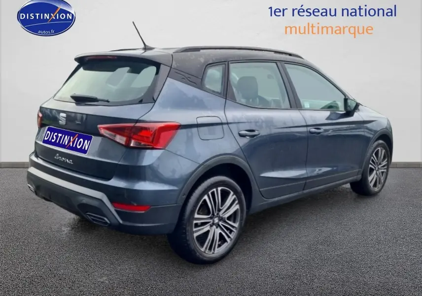 Vue 3/4 arrière droite d'une SEAT Arona gris magnétique avec jantes 17 pouces et barres de toit visibles.