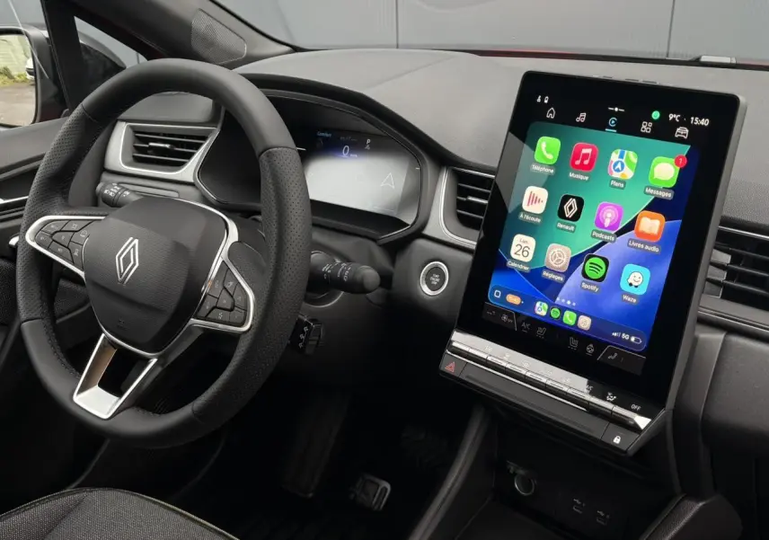 Vue intérieure côté conducteur du Renault Captur 2025, avec volant multifonction et grand écran tactile vertical.