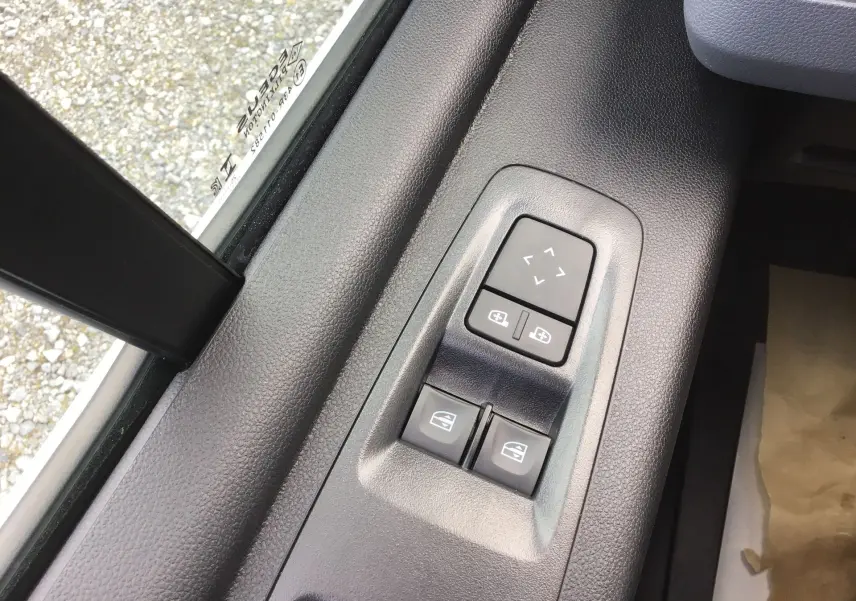 Gros plan sur les commandes électriques des vitres et rétroviseurs côté conducteur du Renault Master blanc 2025.
