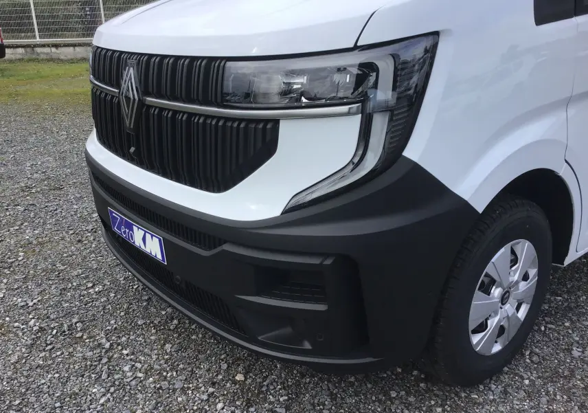 Gros plan sur l’avant droit du Renault Master blanc 2025, mettant en valeur la calandre noire et le phare moderne.