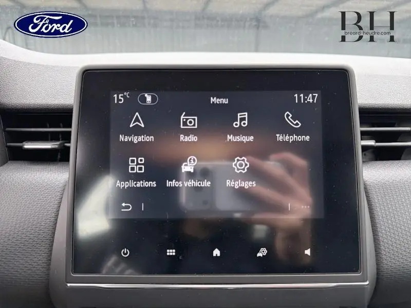 Écran tactile central de la Renault Clio blanche, affichant le menu multimédia avec navigation et radio.