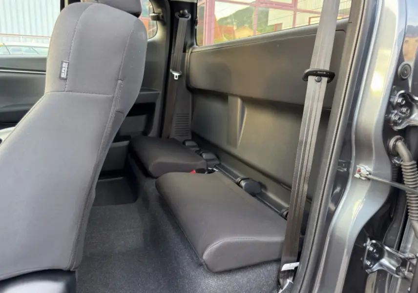 Vue intérieure côté droit du pick-up Isuzu D-MAX 2026 gris obsidian, montrant les sièges arrière rabattus en tissu noir.