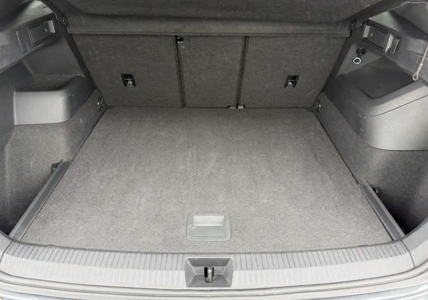 Coffre ouvert vu de l'arrière du Volkswagen Tiguan gris, espace de chargement propre et vide avec revêtement gris.