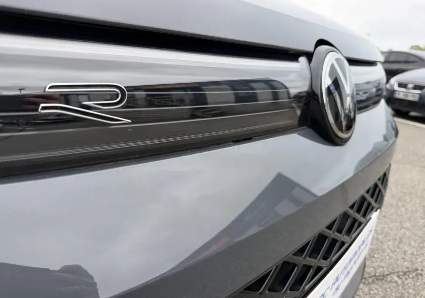 Gros plan sur la calandre avant grise métallisée du Volkswagen Tiguan 2025 avec logo VW et badge R distinctif.