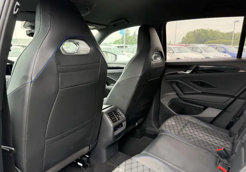 Vue intérieure arrière du Volkswagen Tiguan gris, sièges avant sport noirs avec surpiqûres bleues et banquette arrière en tissu et cuir.