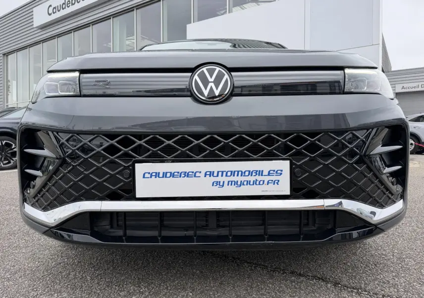 Vue frontale rapprochée du Volkswagen Tiguan gris 2025 avec calandre noire en losange et logo VW lumineux.