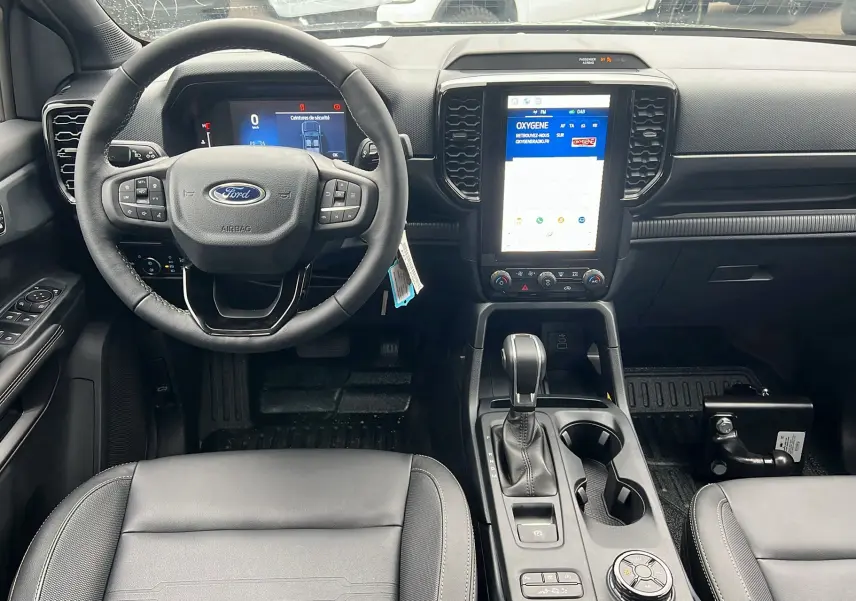 Vue intérieure avant du Ford Ranger 2025, volant cuir multifonctions et écran tactile vertical au centre.