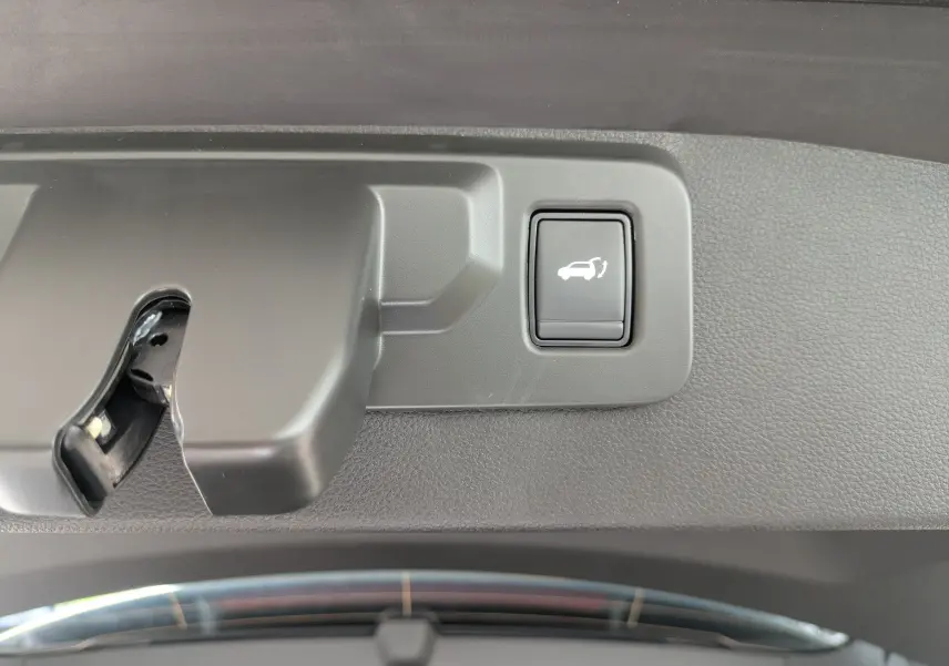 Gros plan sur le bouton d'ouverture électrique du coffre dans l'intérieur gris du Renault Symbioz 2026.