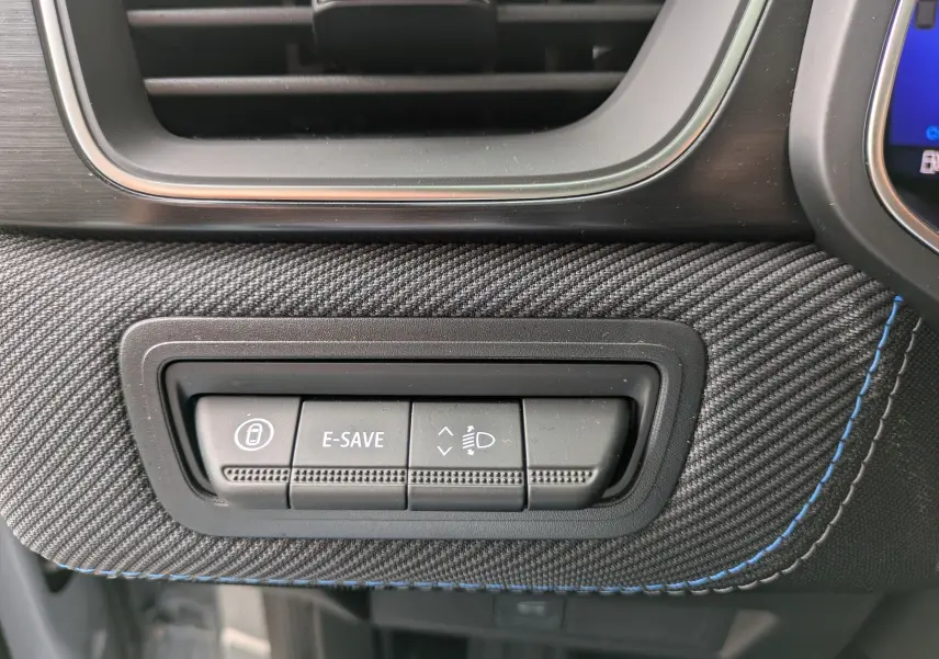 Détail des commandes E-SAVE et réglage des phares sur la planche de bord en tissu gris avec surpiqûres bleues du Renault Symbioz 2026.