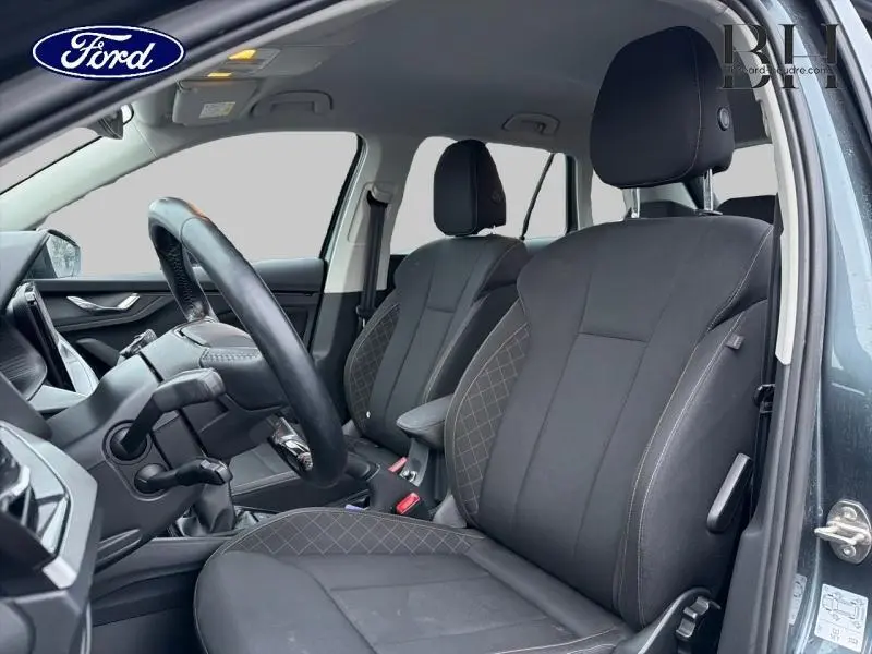 Intérieur avant du Skoda Kamiq 1.0 TSI Business 2021, sièges tissu noir avec surpiqûres grises, volant cuir multifonction visible.