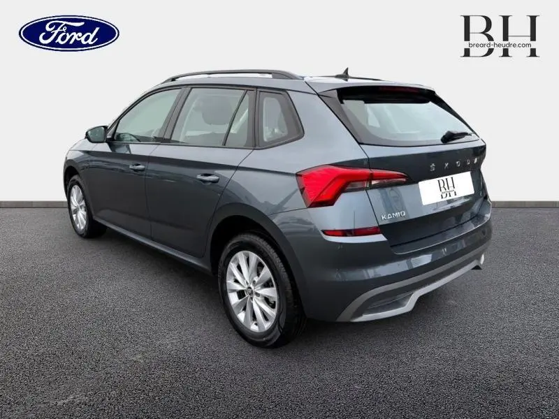 Vue 3/4 arrière droite d'un Skoda Kamiq 1.0 TSI Business gris Météore avec feux arrière LED et jantes alu.