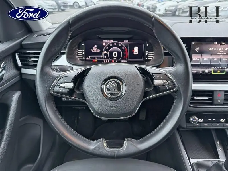 Vue centrée sur le volant cuir noir du Skoda Kamiq gris Météore avec tableau de bord numérique et écran tactile.
