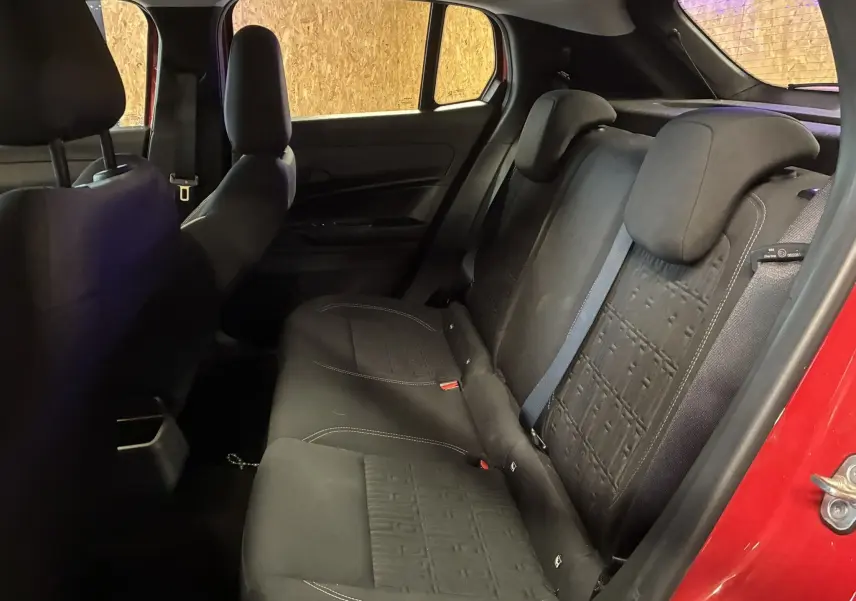 Vue intérieure côté droit des sièges arrière noirs en tissu d'une FIAT 600 1.2 HYBRID 2024 rouge avec portes ouvertes.