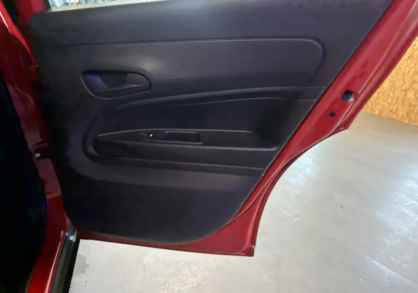 Vue rapprochée de la porte arrière gauche rouge du FIAT 600 1.2 HYBRID 100, intérieur noir avec poignée intégrée.
