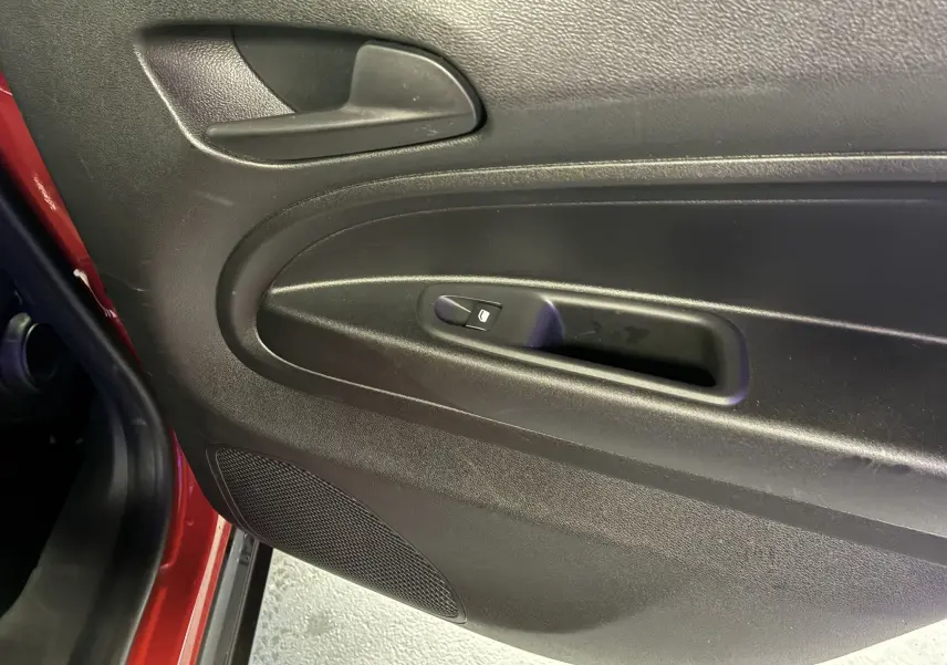 Gros plan sur la porte intérieure côté gauche d'une FIAT 600 rouge 2024, montrant la poignée et le bouton de verrouillage noir.