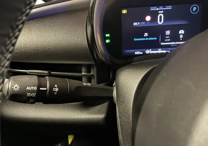 Détail du combiné d'instruments et du commodo d'éclairage à gauche du volant dans la FIAT 600 rouge 2024 hybride.