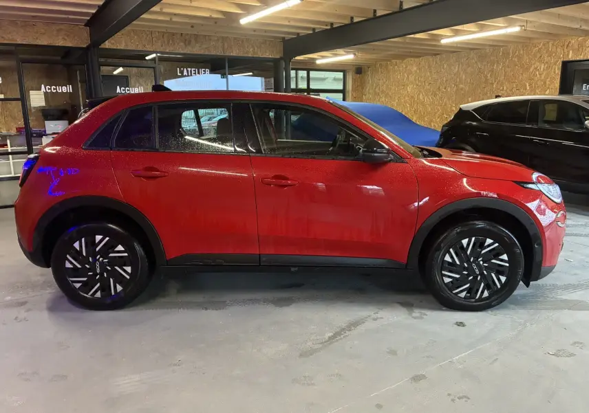 Vue de profil côté gauche d'une FIAT 600 1.2 Hybrid 2024 rouge avec jantes noires et détails noirs sur les bas de caisse.