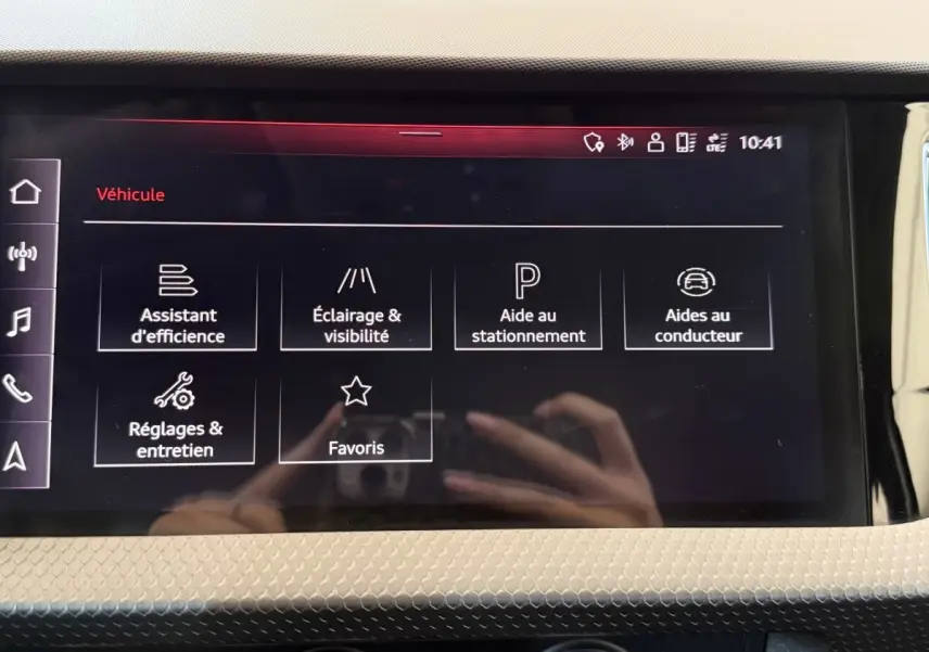 Écran tactile central de l'Audi A1 noir, affichant les menus d'assistance et réglages du véhicule.