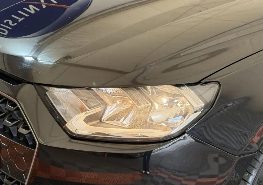 Gros plan sur le phare avant droit et la calandre noire brillante de l'Audi A1 2021 finition Business Line.