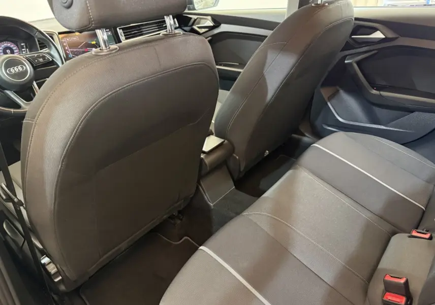 Vue intérieure arrière de l’Audi A1 2021 noire, montrant la banquette tissu et les dossiers des sièges avant.