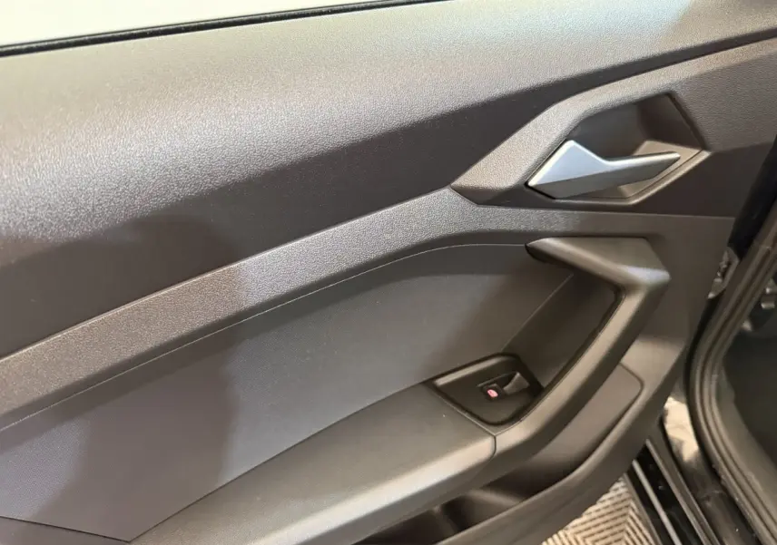 Gros plan sur la porte intérieure côté conducteur noire de l'Audi A1 2021 avec poignée argentée et bouton de lève-vitre.