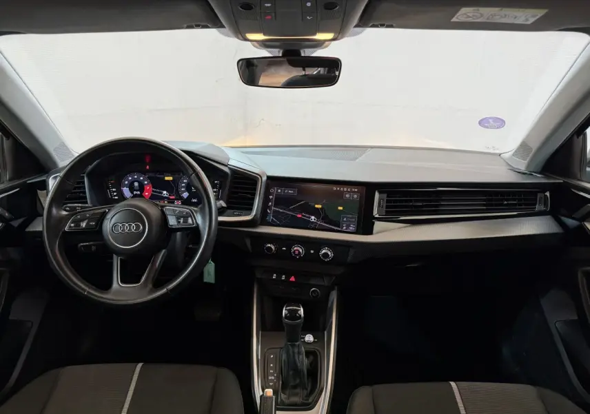 Vue intérieure avant de l'Audi A1 2021 noire, avec volant cuir multifonctions et écran tactile central affichant la navigation.