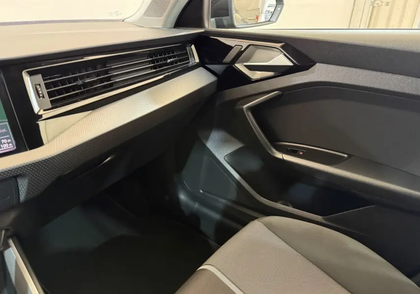 Vue intérieure côté passager de l'Audi A1 2021 noir, mettant en valeur la planche de bord et la portière moderne.