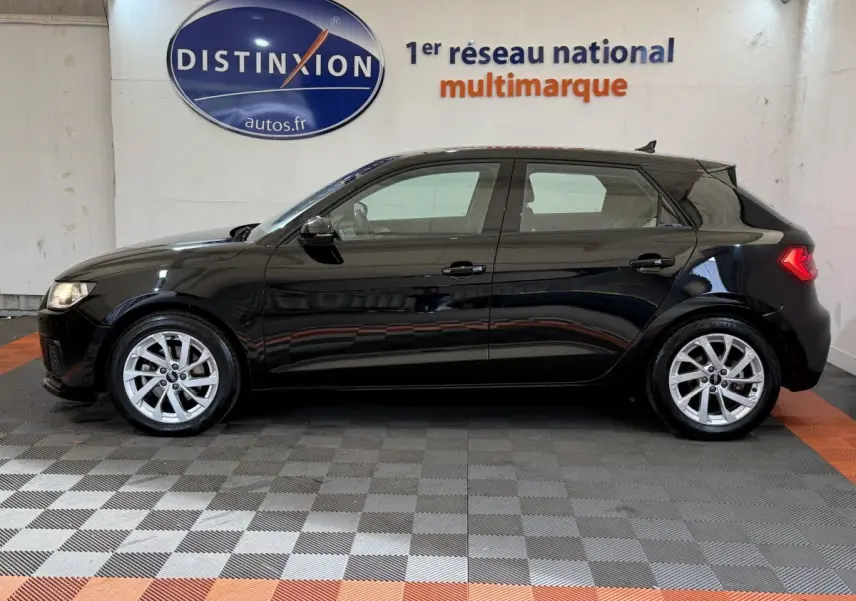 Audi A1 Business Line noire vue de profil côté gauche, avec jantes argentées et feux arrière allumés.