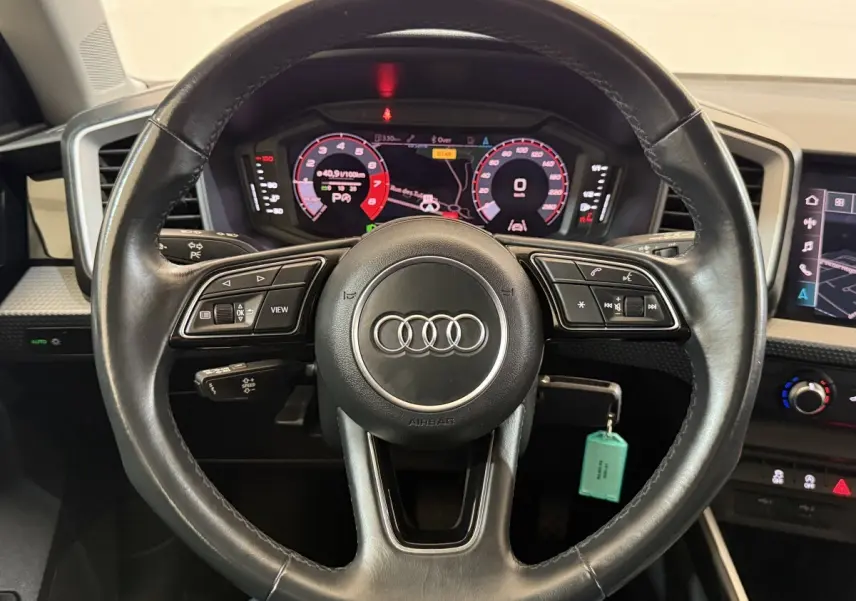 Vue rapprochée du volant cuir multifonctions noir de l'Audi A1 2021 avec tableau de bord numérique et écran tactile.