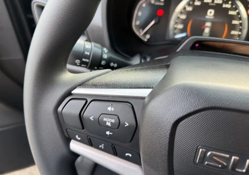 Gros plan sur le volant multifonctions noir de l'Isuzu D-MAX 2026, avec commandes audio et téléphone intégrées.