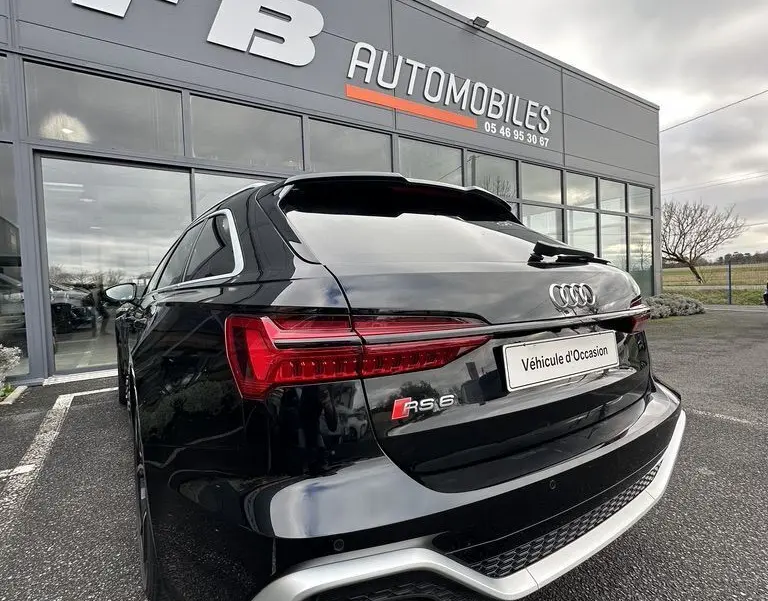 Vue 3/4 arrière droite d'une Audi RS6 Avant noire 2021 avec feux LED et double sortie d'échappement visible.