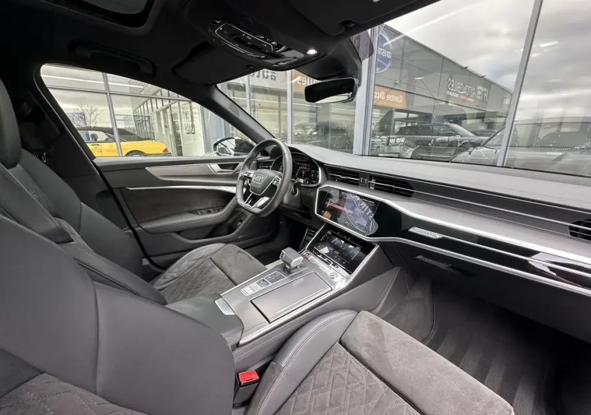 Vue intérieure côté conducteur de l'Audi RS6 Avant 2021 noire, avec tableau de bord digital et finitions cuir et aluminium.