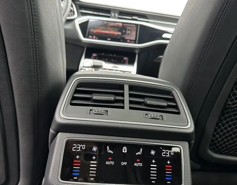 Vue intérieure arrière de l'Audi RS6 Avant 2021 noire, montrant la console de climatisation et les écrans tactiles avant.