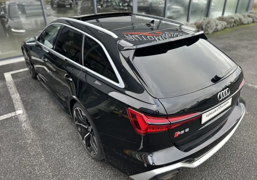 Audi RS6 Avant noire vue en 3/4 arrière droit, avec feux arrière LED et toit ouvrant panoramique visible.