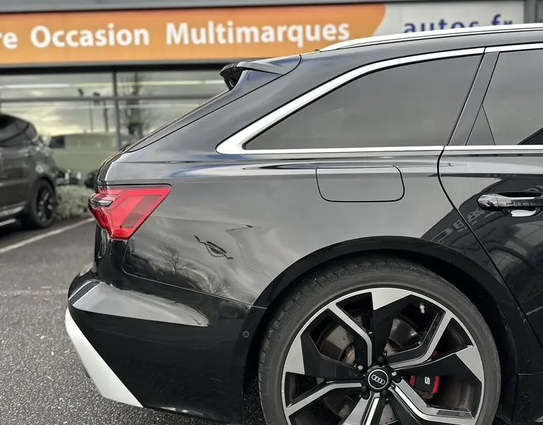 Vue 3/4 arrière côté gauche d'une Audi RS6 Avant noire avec jante alliage sport et vitres teintées.
