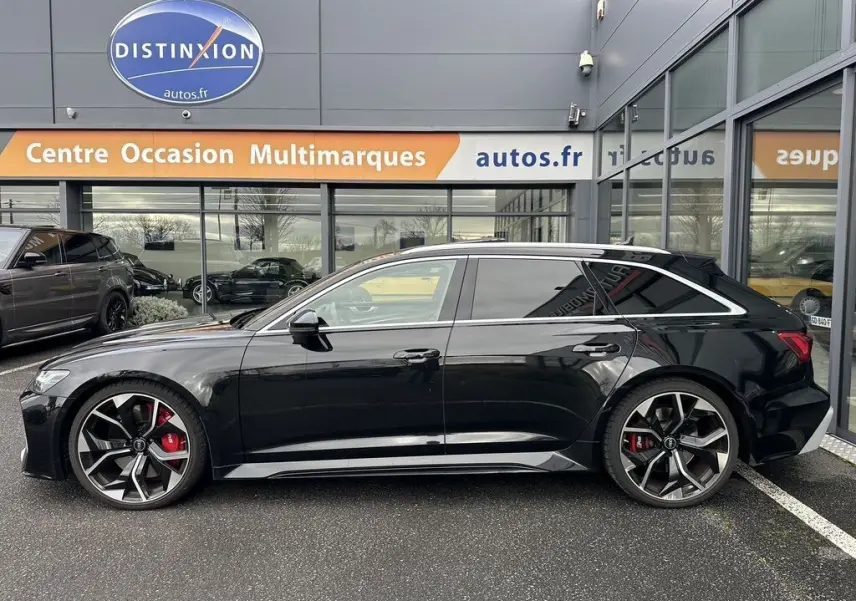 Profil côté gauche d'une Audi RS6 Avant noire 2021 avec grandes jantes alliage et étriers de frein rouges visibles.