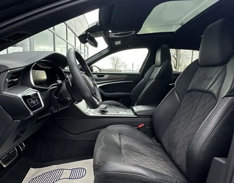 Vue intérieure côté conducteur de l'Audi RS6 Avant 2021 avec sièges en cuir noirs et toit ouvrant panoramique.