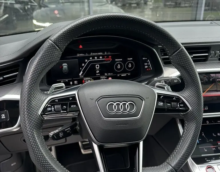 Volant perforé noir de l'Audi RS6 Avant 2021 avec affichage numérique et commandes intégrées vues de face depuis le poste de conduite.