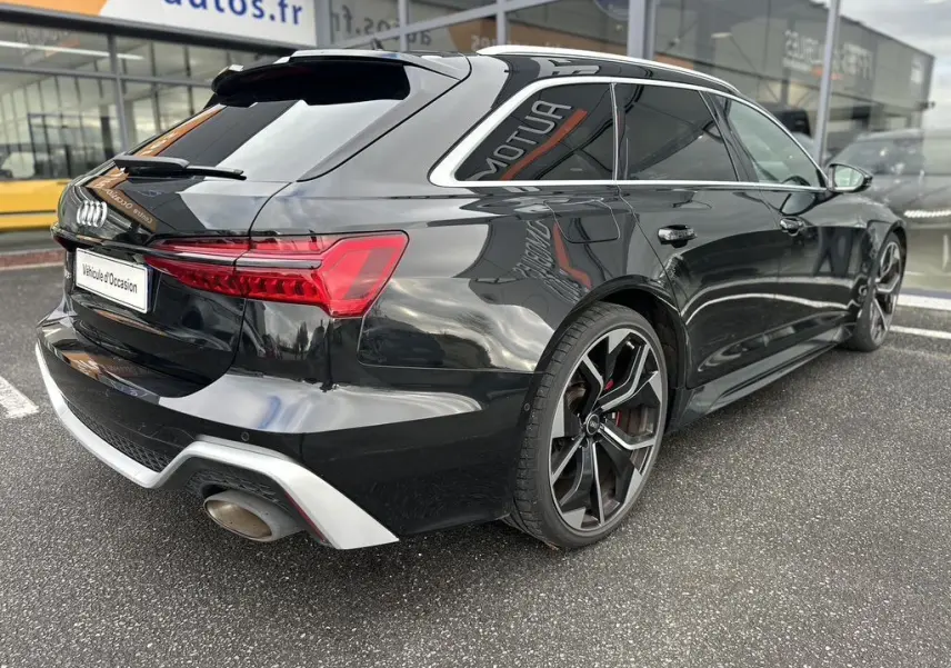 Audi RS6 Avant noire vue en 3/4 arrière droit, avec jantes sport et feux arrière LED distinctifs.