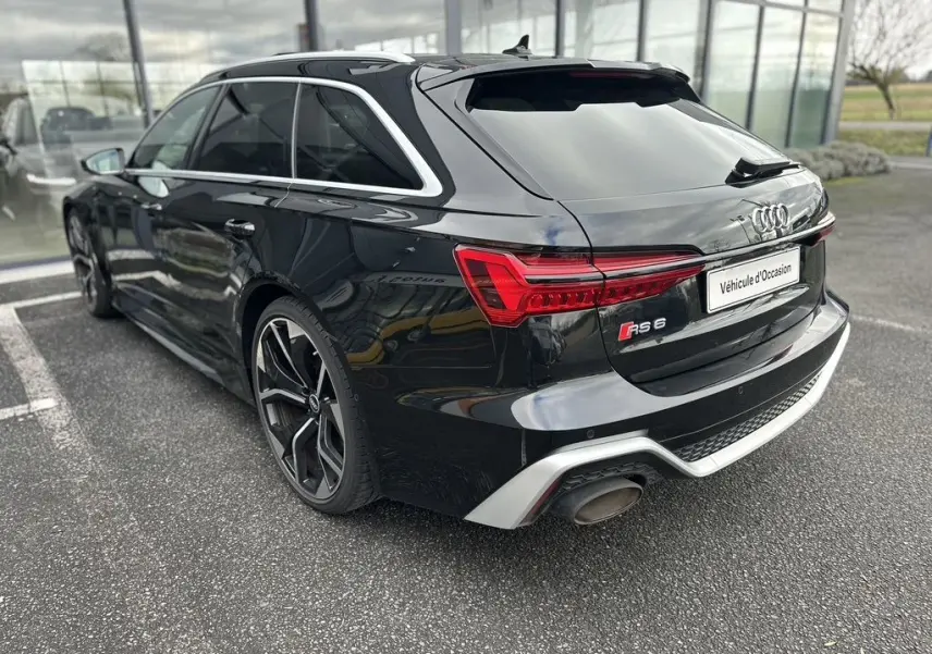 Audi RS6 Avant noire vue en 3/4 arrière droit, mettant en valeur ses feux LED et ses jantes sportives distinctives.
