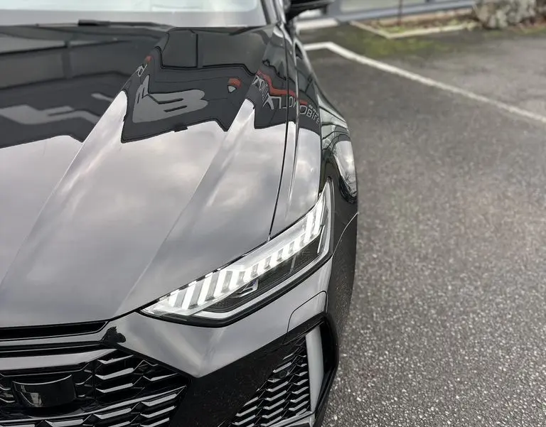 Vue rapprochée 3/4 avant droit de l'Audi RS6 Avant noire avec phares LED et calandre sportive.