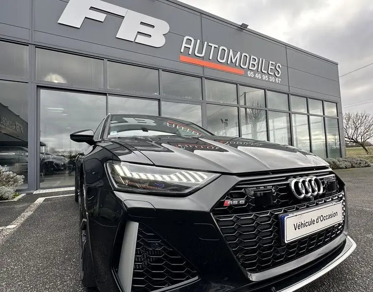 Audi RS6 Avant noire vue en 3/4 avant droit, mettant en valeur sa calandre hexagonale et ses phares LED distinctifs.