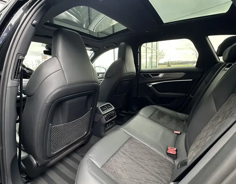 Vue intérieure arrière de l'Audi RS6 Avant noire 2021, montrant les sièges en cuir et le toit ouvrant panoramique.