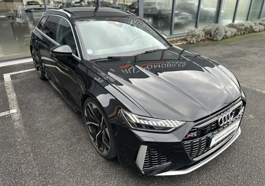 Audi RS6 Avant noir vue 3/4 avant droit, avec calandre distinctive et jantes sportives noires et rouges.