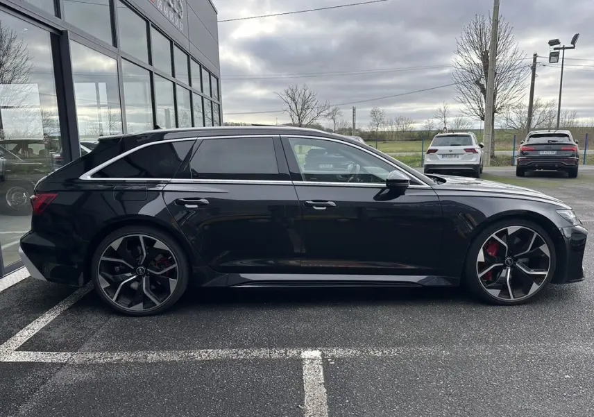 Audi RS6 Avant 2021 noire vue de profil côté gauche, avec jantes sport et étriers de frein rouges visibles.