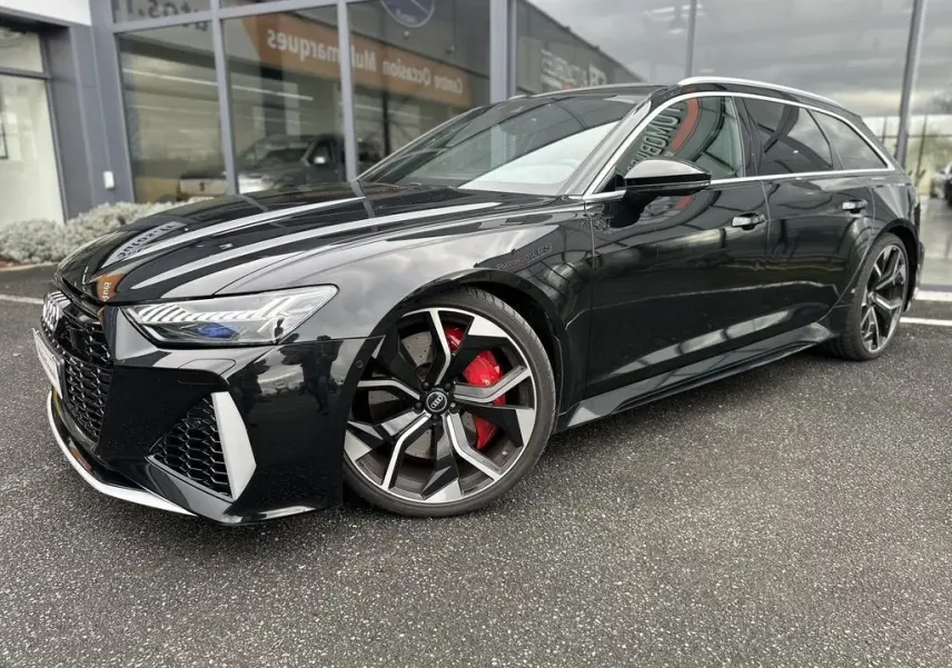 Audi RS6 Avant noire vue en 3/4 avant droit, avec jantes sport et étriers de frein rouges visibles.