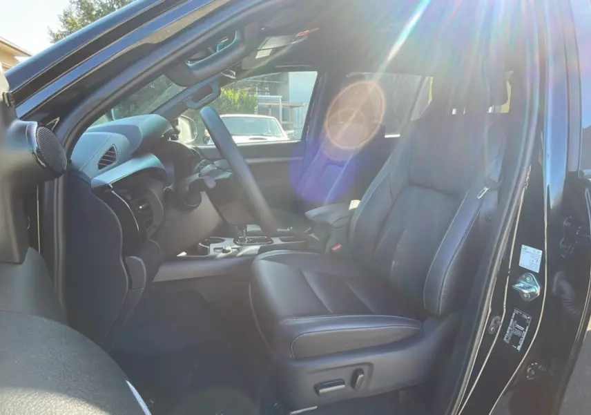 Intérieur du Toyota Hilux 2025 noir attitude, vue côté conducteur avec sièges cuir et tableau de bord moderne.